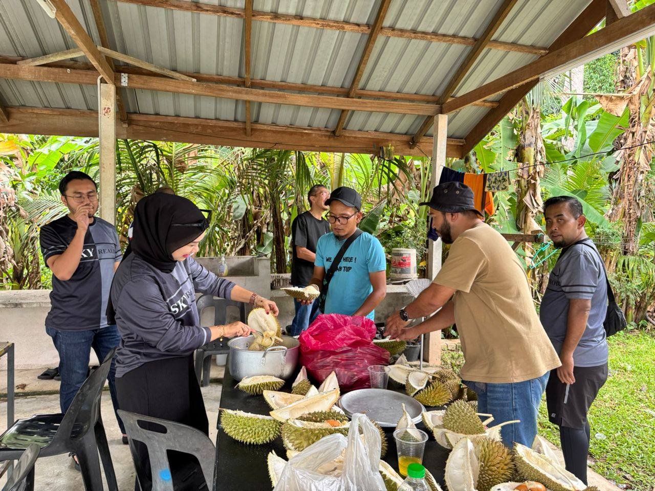 People sharing durian under a covered shelter during Avenia Family Day.