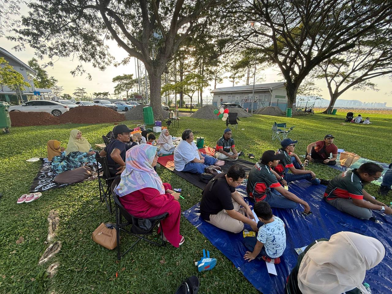 People seated on picnic mats beneath trees at R&R Bagan Ajam.